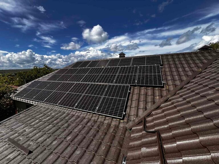 Panouri fotovoltaice monocristaline montate pe acoperiș de țiglă metalică, cer senin — instalare ePrime